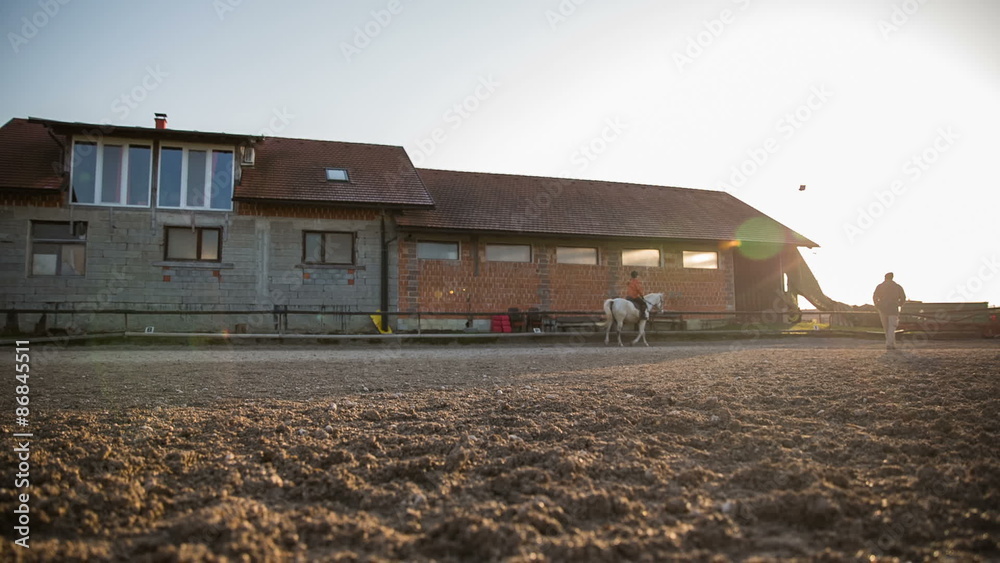 Ranch with woman riding horse at sunset wide shot Ranch with woman riding horse at sunset wide shot