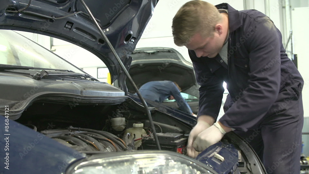 Teacher Helping male Student Training To Be Car Mechanic Teacher Helping male Student Training To Be Car Mechanic