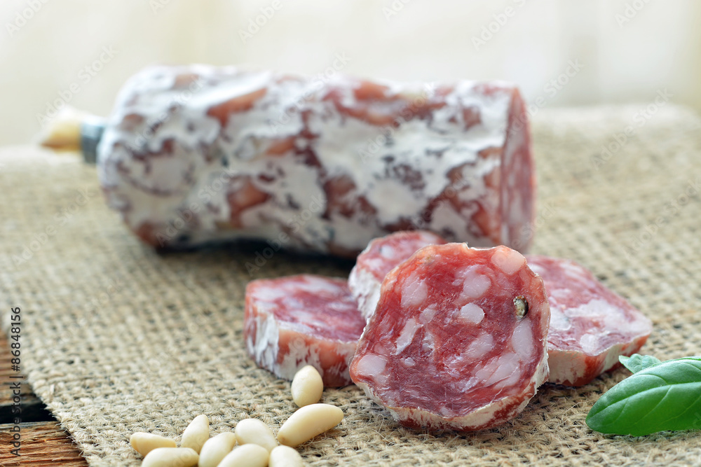 Salami (Rohwurst), auf Jute, Pinienkerne, Basilikum Salami (Rohwurst), auf Jute, Pinienkerne, Basilikum