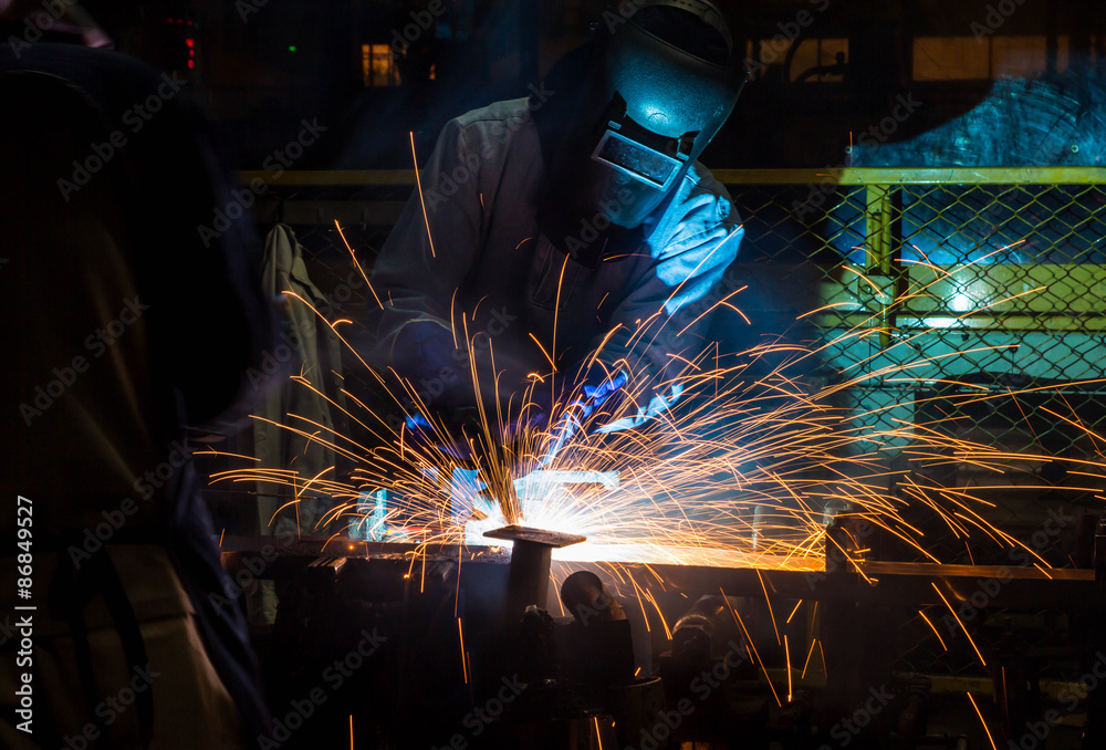 Welder working in a steel factory with sparks flying Welder working in a steel factory with sparks flying