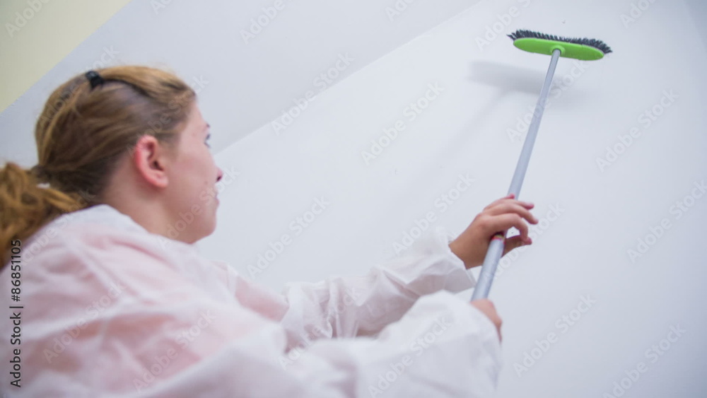 Woman cleaning spiderwebs from walls with broom Woman cleaning spiderwebs from walls with broom