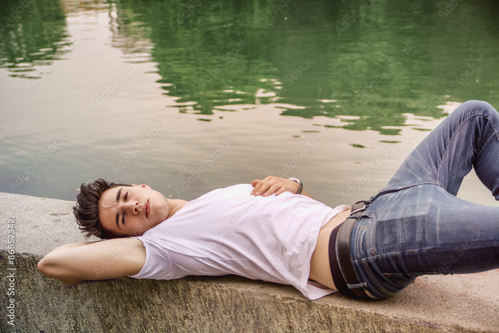 Handsome young man on a lake's shore or river banks