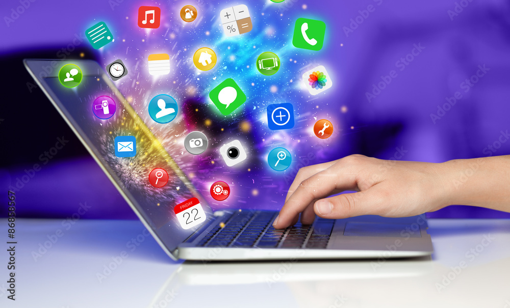 Hand pressing modern laptop with mobile app icons and symbols Hand pressing modern laptop with mobile app icons and symbols