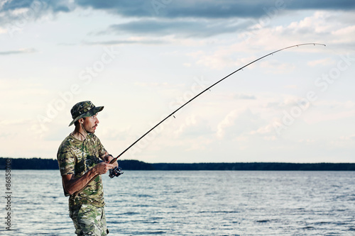 Surprised man caught a fish on the lake during his vacation