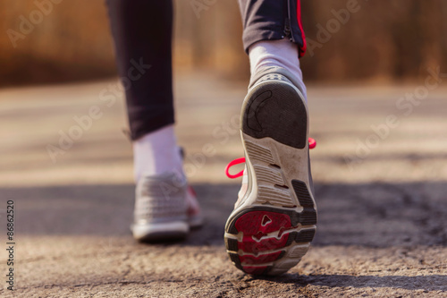 Runner feet with sport shoes on road