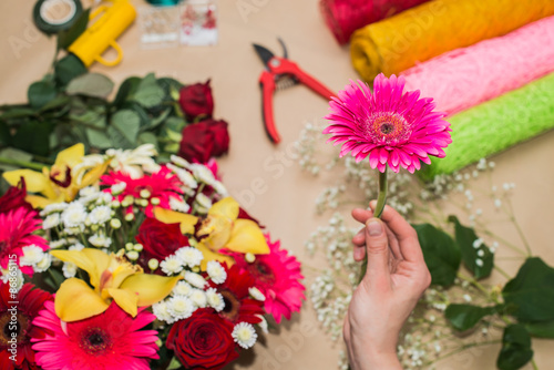 Fototapeta Naklejka Na Ścianę i Meble -  Florist at work. Woman making bouquet of flowers. One gerbera in