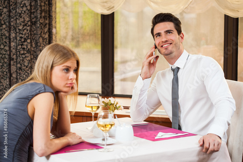 Woman is bored at restaurant, her boyfriend talks on the phone