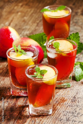 Peach Tea with pieces of fruit and mint on a wooden background,