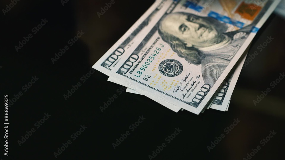 Hands spread banknotes of hundred dollars on the table Hands spread banknotes of hundred dollars on the table