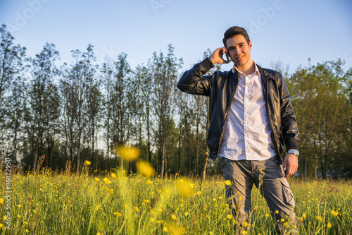Handsome young man at countryside, using cell phone