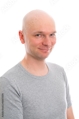 young man with bald head is smiling in to the camera