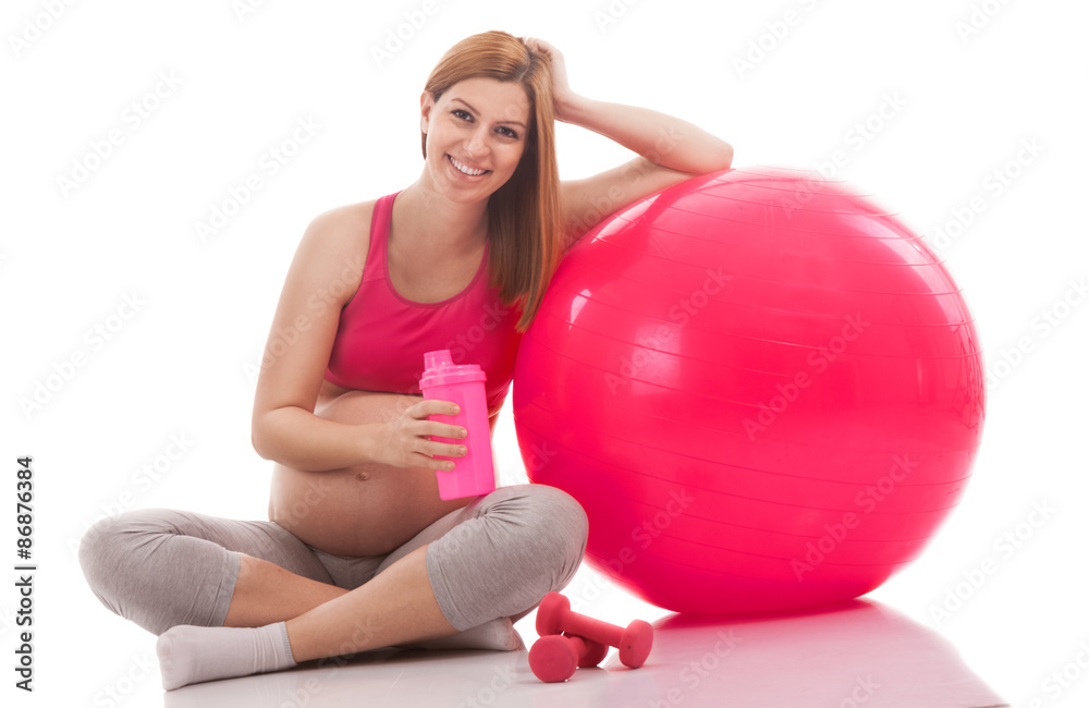 Pregnant young woman relaxing after training with drink and ball Pregnant young woman relaxing after training with drink and ball