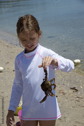 Little girl holding a crab at the seasise. Long island USA photo