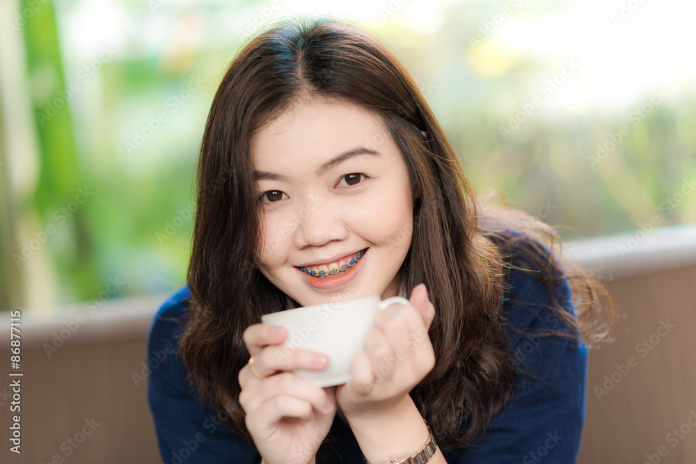 Happy asian smiling female student drinking coffee