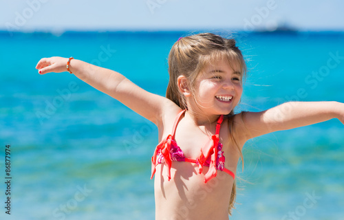 Bambina al mare che ride e gioca, mare turchese come sfondo