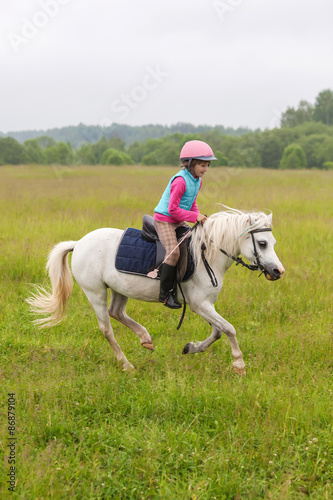 Beautiful baby girl on a white horse galloping across the field Outdoors © andreipugach