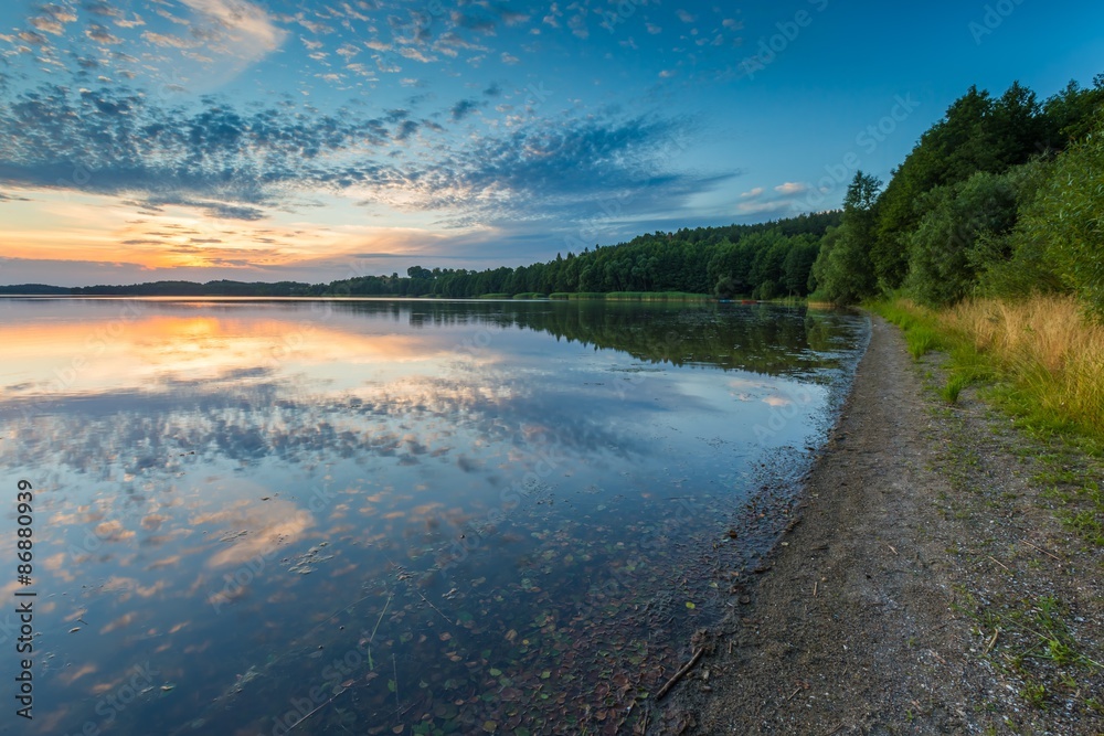 Fototapeta premium Beautiful lake at sunset landscape with cloudy sky reflecting in water