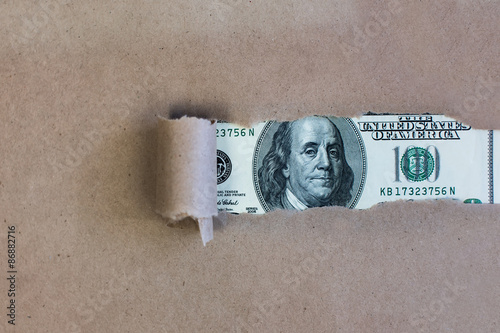 Dollars through torn green paper