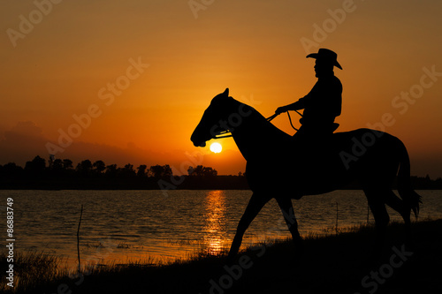 silhouette of Cowboy sitting on his horse at sunset background