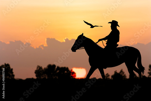 silhouette of Cowboy sitting on his horse at river full moon after sunset background