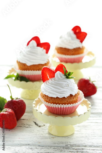 Tasty cupcake with strawberry on cake stand on white wooden back