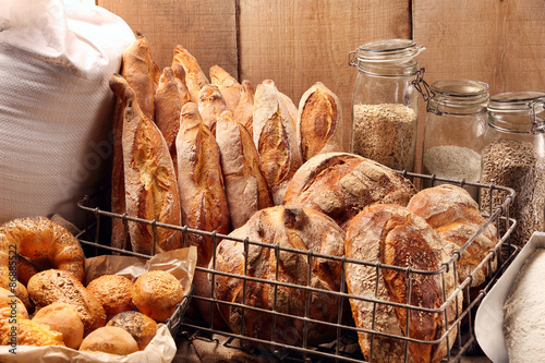 Fresh bread in metal basket in bakery on wooden background photo