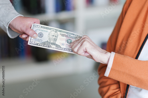 Zwei Frauen ziehen an einem Geldschein/Generationskonflikt, alte Frau und junge Frau ziehen an einem Dollar Geldschein.