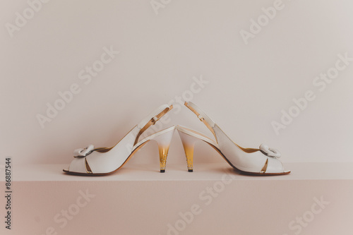 White wedding shoes with a bow on wood background