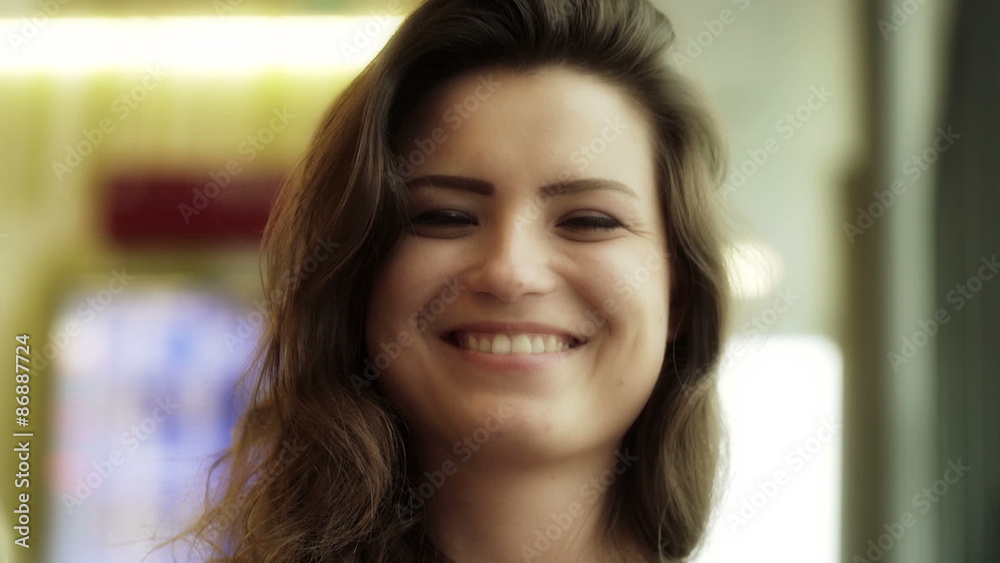 Woman using cellphone and smiling to the camera at the airport, steadycam shot
