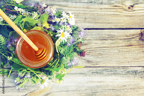 Honey in a glass jar with June flowers melliferous herbson a wooden surface. Honey with flowers photo