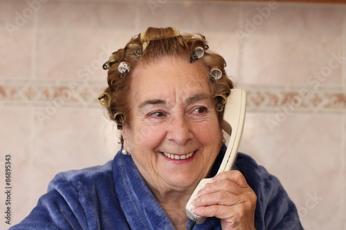 Funny housewife in hair curlers wearing blue robe photo