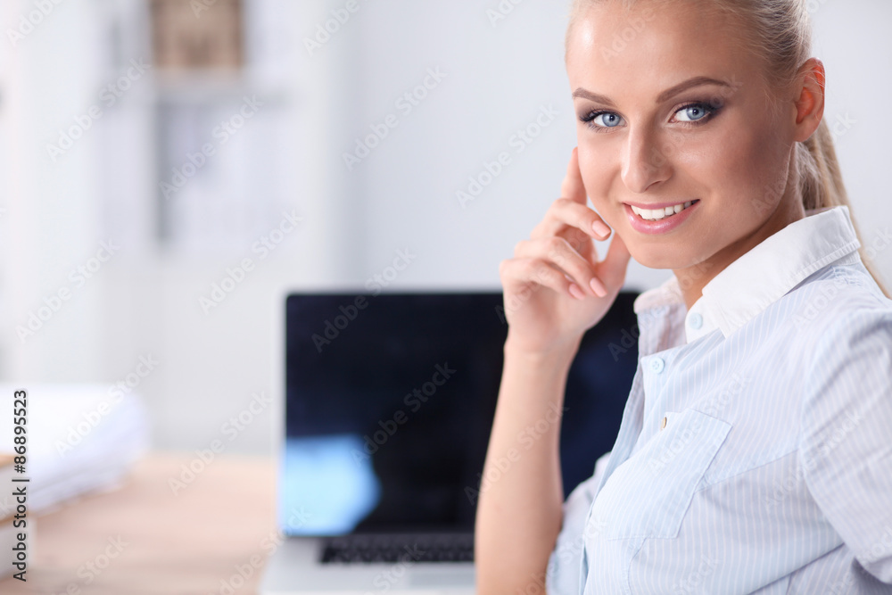 Attractive businesswoman sitting on a desk with laptop in the Attractive businesswoman sitting on a desk with laptop in the