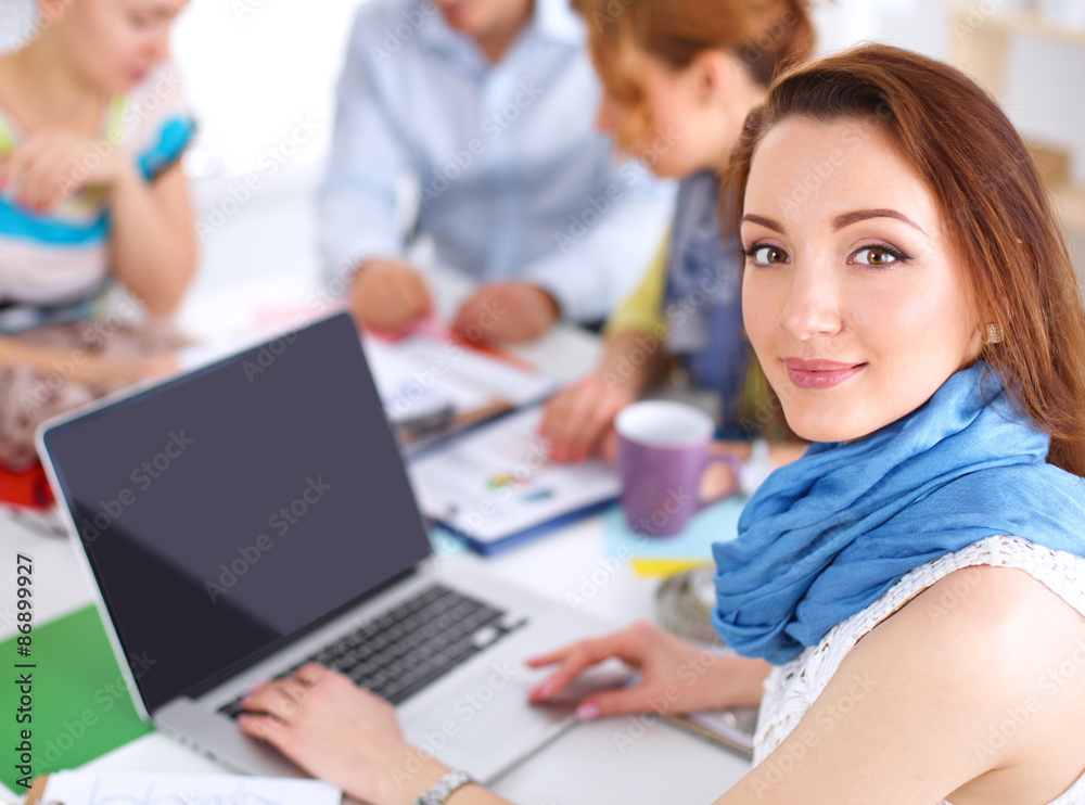 Portrait of attractive female designer sitting on desk in Portrait of attractive female designer sitting on desk in