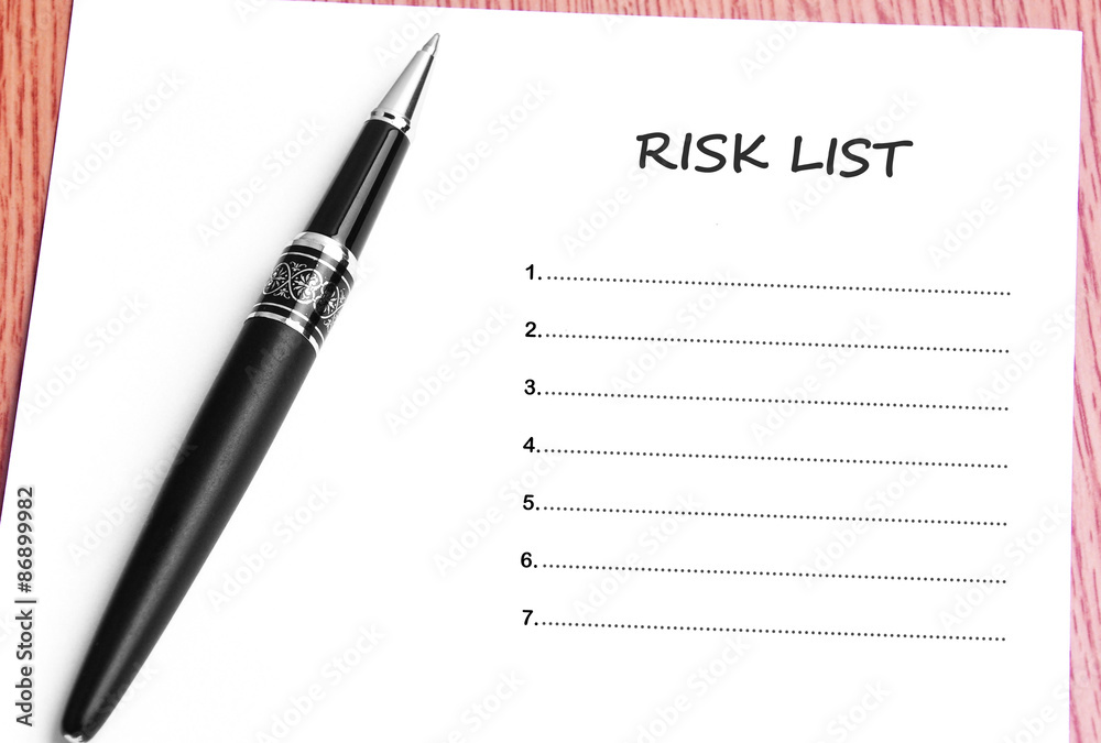 Pen and notes paper with risk list Pen and notes paper with risk list