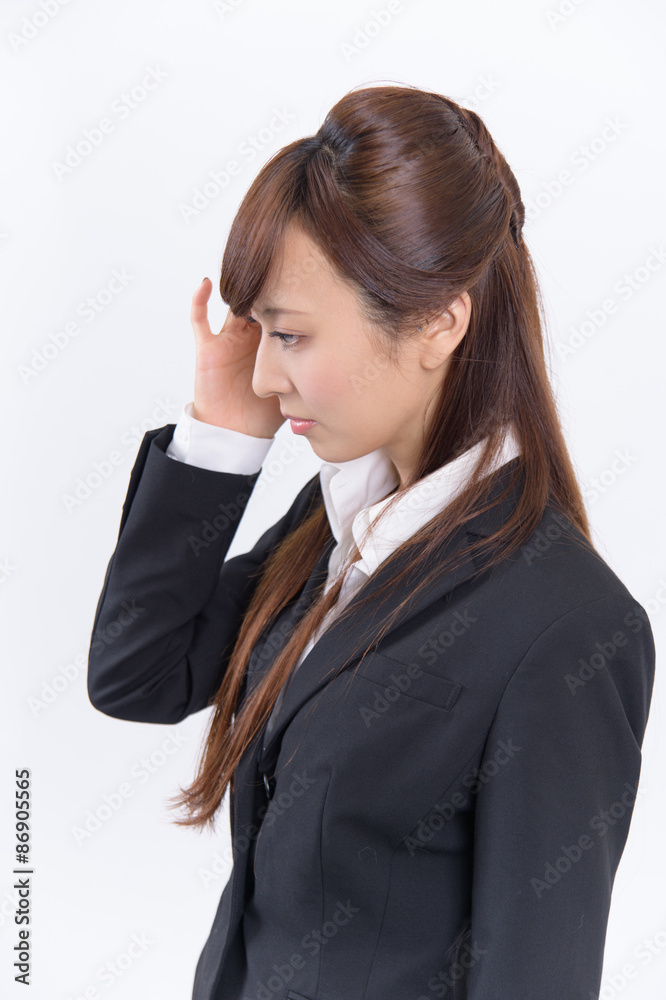 頭を抱え悩める若いスーツ姿の日本人女性