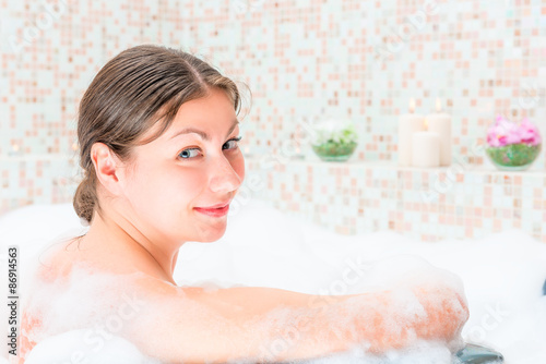 young beautiful woman taking a bath with foam