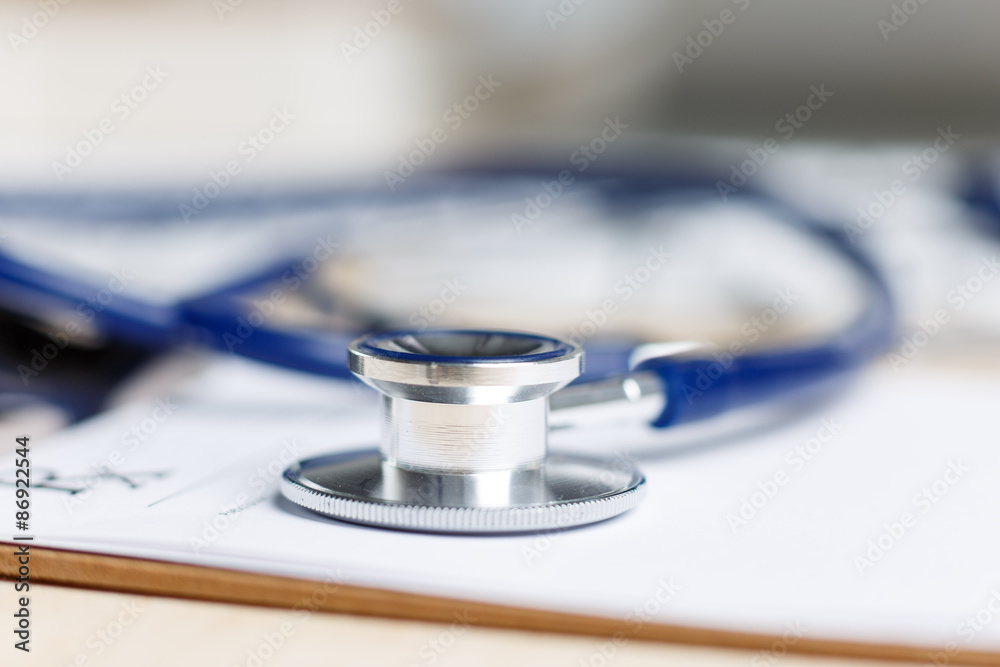 Prescription form clipped to pad lying on table with stethoscope Prescription form clipped to pad lying on table with stethoscope