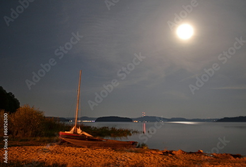 Boat on a lake shore at night in the moonlight