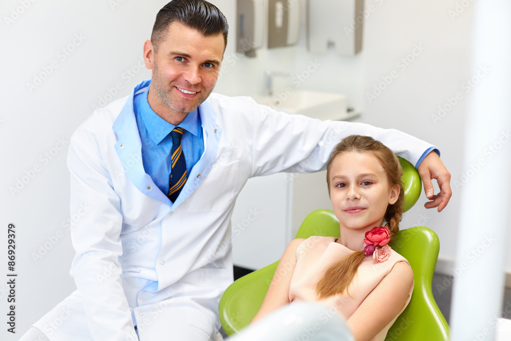Dentist Examining Little Girls Teeth in The Dentists Chair at the Dental Clinic