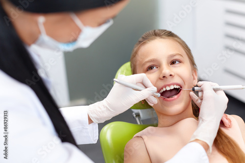Fototapeta Naklejka Na Ścianę i Meble -  Teeth checkup at dentist's office. Dentist examining girls teeth