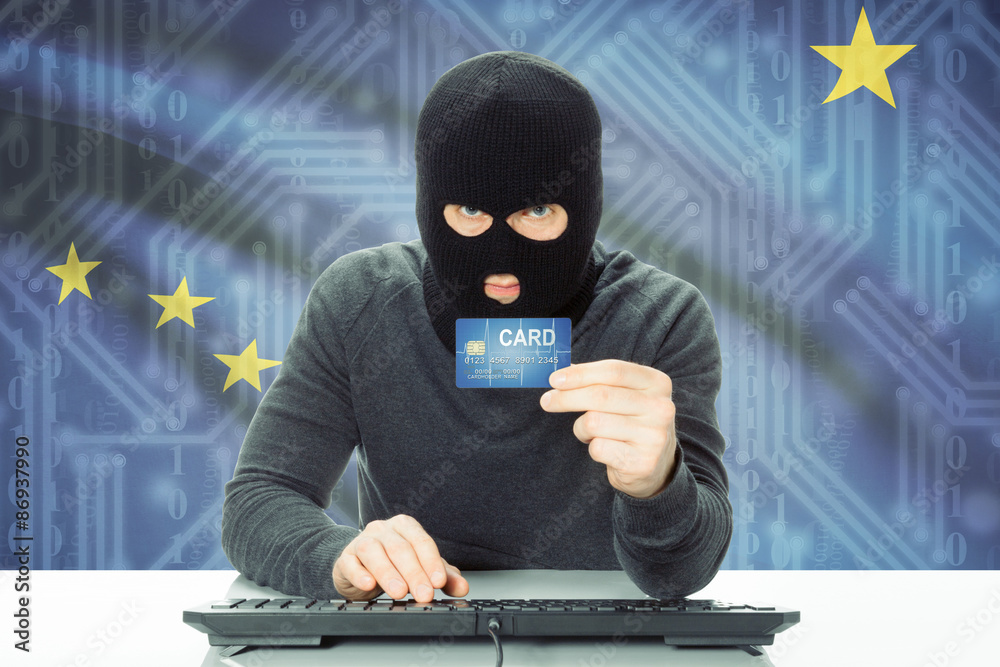 Hacker holding credit card and USA state flag on background - Alaska Hacker holding credit card and USA state flag on background - Alaska