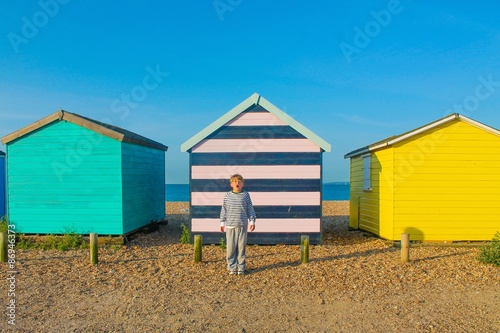 CHILD IN FRONT OF A LINE OF BEACH HUTS