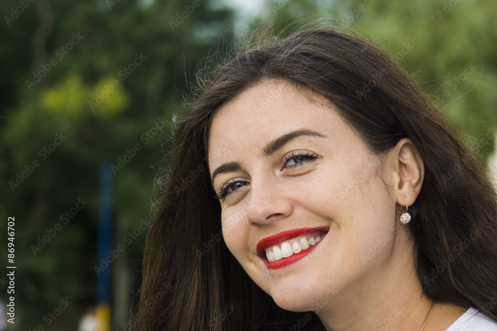 Portrait of smiling beautiful young woman close-up, against green of summer park Portrait of smiling beautiful young woman close-up, against green of summer park