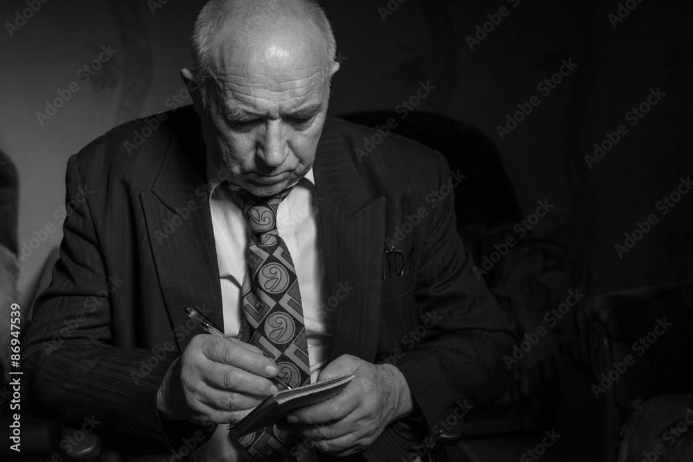 Fototapeta premium Old Businessman Writing Some Notes in Monochrome