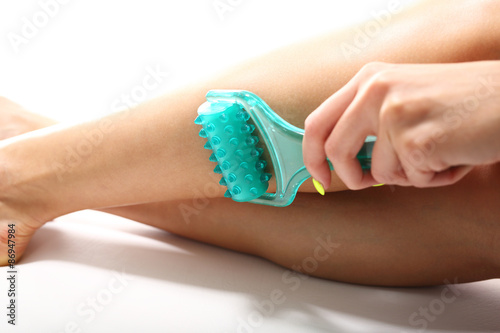 Masaż łydki. Kobieca noga podczas zabiegu masażu rolką kosmetyczną. 