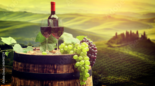 Fototapeta Naklejka Na Ścianę i Meble -  Red wine bottle and wine glass on wodden barrel. Beautiful Tusca