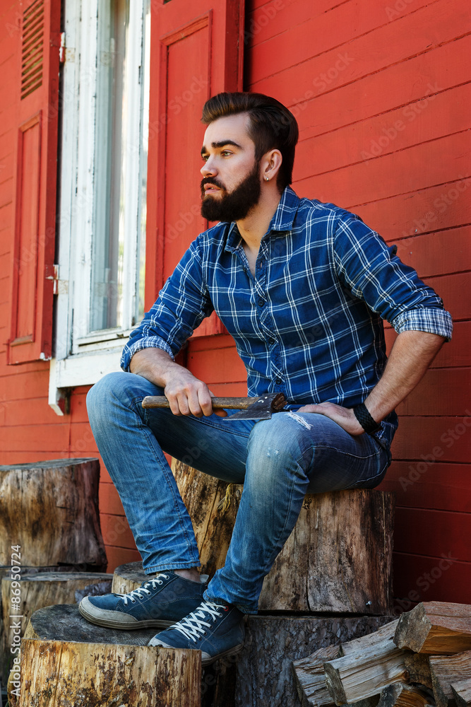 Handsome bearded man sitting on stump Handsome bearded man sitting on stump