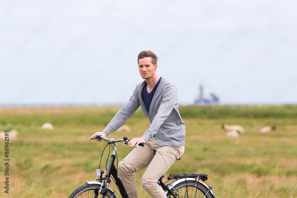 Mann bei Radtour mit dem Fahrrad am Deich mit Schafen Mann bei Radtour mit dem Fahrrad am Deich mit Schafen