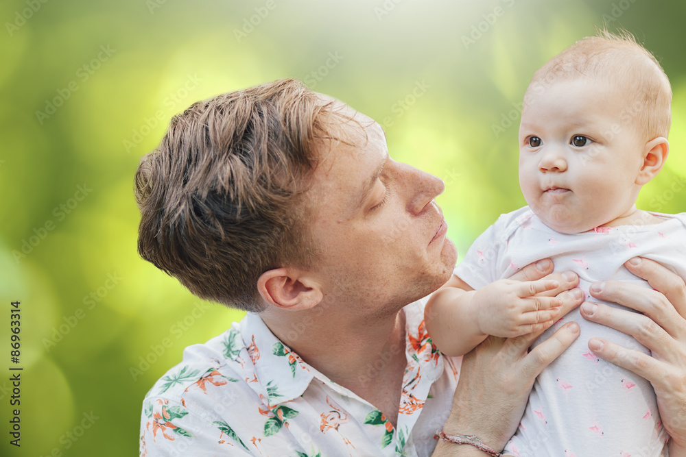 Cute happy baby laughing with his father having fun outdoors in Cute happy baby laughing with his father having fun outdoors in