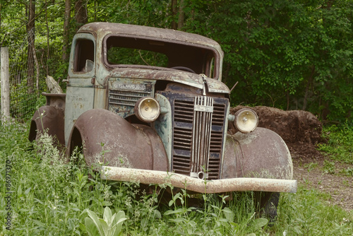 An old rustic antique truck sits in green grass.